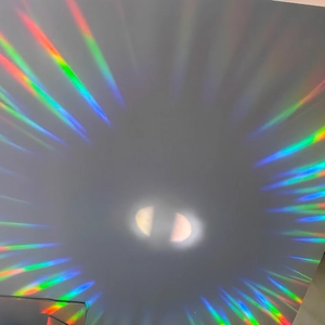 Rainbow suncatcher prism projecting vibrant colorful light beams on a white wall