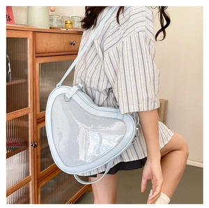 Light blue heart-shaped Ita bag with clear window and adjustable strap on a model