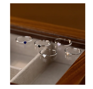Detail view of five multi-colored heart-cut cubic zirconia rings in a velvet jewelry box