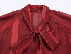 Close-up of wine red striped blouse featuring a neck tie bow and shiny fabric texture