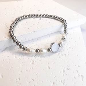 Detail of beaded stainless steel bracelet featuring baroque pearls and a round charm disc
