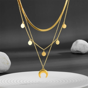 Three-layer gold titanium steel necklace with horn pendant and round disks on a white tray