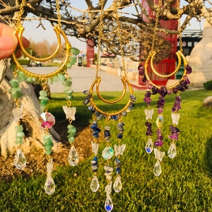 Detailed close-up of crescent moon suncatchers with butterfly charms and colorful crystals