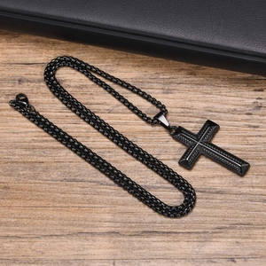 Detailed view of black stainless steel cross pendant with textured finish and woven chain