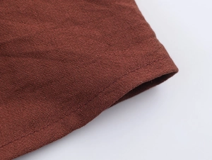 Macro shot of rust red cotton linen fabric detail showing textured weave and natural fibers