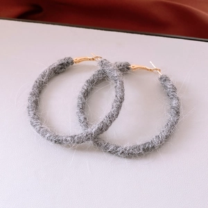 Detailed view of grey wool knit hoop earrings with warm winter texture and gold metal clasp