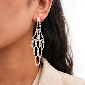 Close-up of a silver-tone fan-shaped tassel earring with rhinestones on a female model
