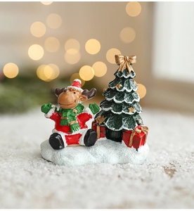 Détail de figurine de Noël en résine avec renne, sapin et boîte cadeau sur neige