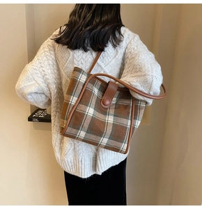 Close-up of vintage plaid wool tote bag with brown leather handles and magnetic closure