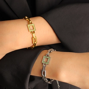 Detail of gold and silver square link bracelets with green zircon inlay on wrist