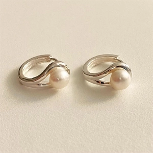 Detail of silver hoop earrings with elegant crossover design and white pearl center