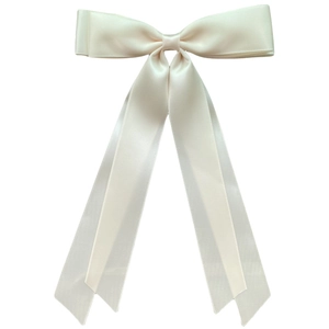 Detail of white satin ribbon bow hair clip with smooth texture and long elegant streamers