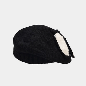 Close-up of black knitted beret with white bunny ear accents and fine ribbed edges