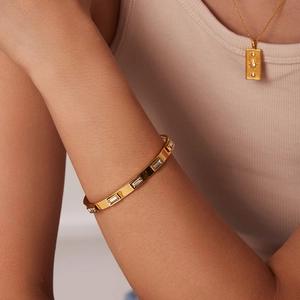 Gros plan d'un bracelet en acier inoxydable doré avec zircon vert rectangulaire