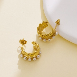 Close-up of C-shaped gold-plated hoop earrings with elegant white pearl insets