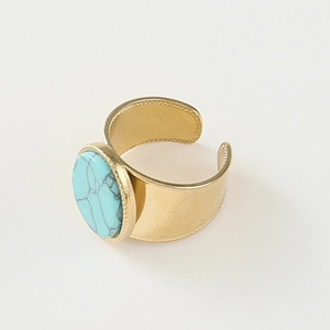 Detail view of gold wide band ring featuring turquoise stone with beaded edge detailing