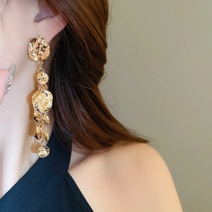 Gros plan de boucles d'oreilles pendantes dorées à disques superposés sur un modèle