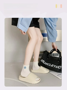 Close-up of white platform sports slides worn with cotton socks in a casual setting