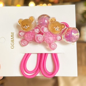 Gros plan d'élastiques à cheveux roses avec ours en résine et boules à paillettes