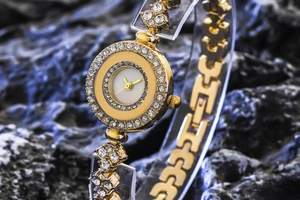 Close-up of luxury women's gold quartz watch with pavé diamonds on a mineral stone base