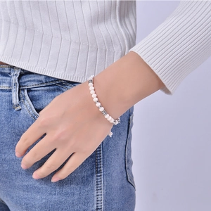 Close-up of bohemian white bead bracelet with silver spacers worn on woman's wrist