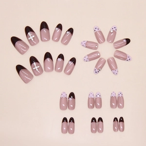 Detailed flat lay of pink French cat-eye press-on nails with star and cross rhinestones