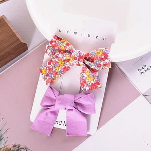 Detail of floral and purple handmade bow hair clips on display card for girls