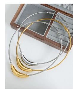 Macro shot of minimalist gold and silver curved bar pendants on sleek snake chains
