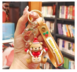 Handheld view of Christmas bear keychain with festive hat and Merry Christmas strap
