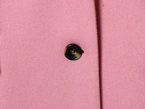 Macro del tessuto misto lana rosa con un dettaglio di bottone in ambra scura di pregio