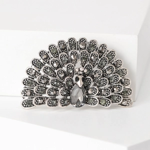 Detail view of a vintage silver peacock brooch with sparkling dark grey rhinestones