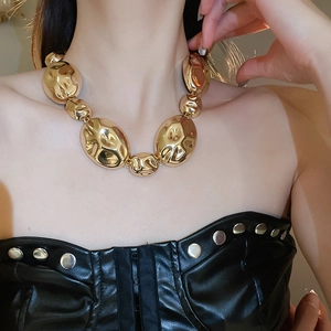 Detail of oversized gold oval link necklace with textured finish on female model
