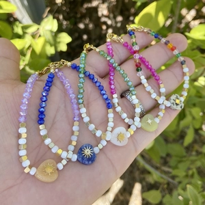 Detail view of colorful beaded heart bracelets with gold sun pendants on natural stones
