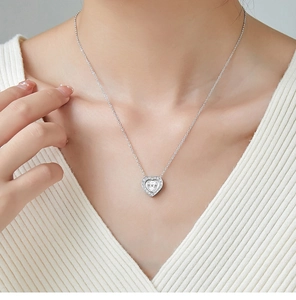 Close-up of heart pendant necklace on collarbone showing elegant drape and silver finish