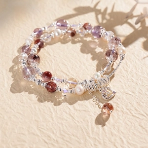 Macro view of multi-layer beaded bracelet with amethyst, tiger eye, and pearls