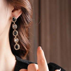Détail de boucles d'oreilles vintage dorées avec strass noirs et clairs sur modèle