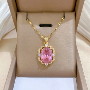 Macro shot of gold pendant with oval pink stone and micro-pave crystals in a jewelry box