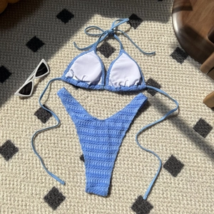 Detail of sky blue smocked bikini set with drawstring ties on textured woven background