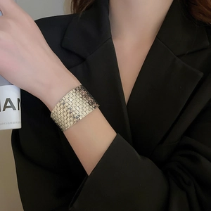 Detail shot of wide silver textured cuff bracelet with woven pattern on model wrist