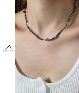 Detail of beaded necklace with blue natural stones and stainless steel gold spacers