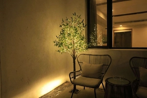 Detail of warm white LED olive tree lights with green leaves on a cozy outdoor terrace