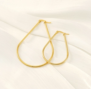 Detail of gold teardrop hoop earrings on white silk fabric with latch back closures