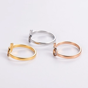 Three minimalist OT letter rings in gold, silver and rose gold on a clean background