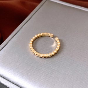 Detail of gold plated ring featuring wave bead texture on a gray brushed jewelry box