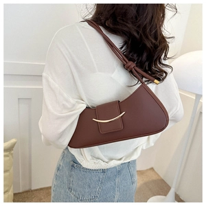 Detail view of brown croissant bag with golden crescent clasp and knotted shoulder strap