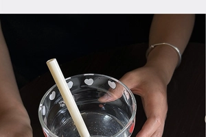 Detail of high borosilicate heat-resistant glass cup with straw and red heart patterns