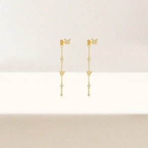 Macro detail of gold-plated butterfly tassel earrings with sparkling zircon stones
