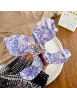 Détail d'une pince à cheveux papillon marbrée violette et blanche pour une coiffure élégante