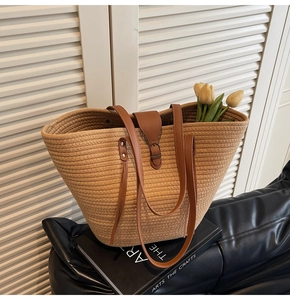 Close-up of woven tote bag with brown leather handles on a decorative book base