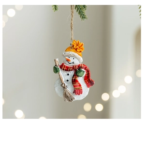 Detailed view of a resin snowman ornament with broom hanging on a festive pine branch